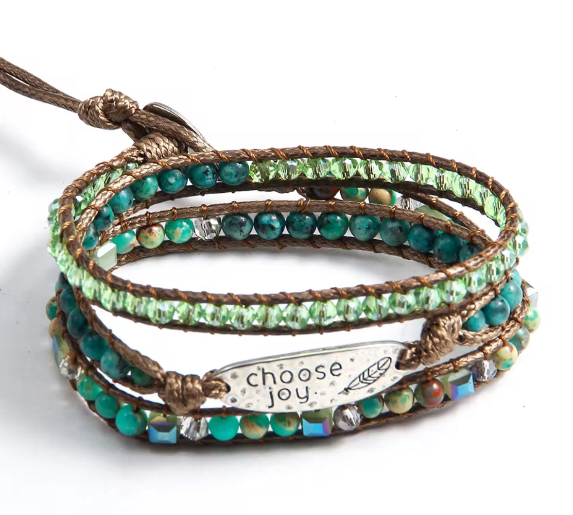 Multistrand bracelet with green beads and 'choose joy' charm on a white background