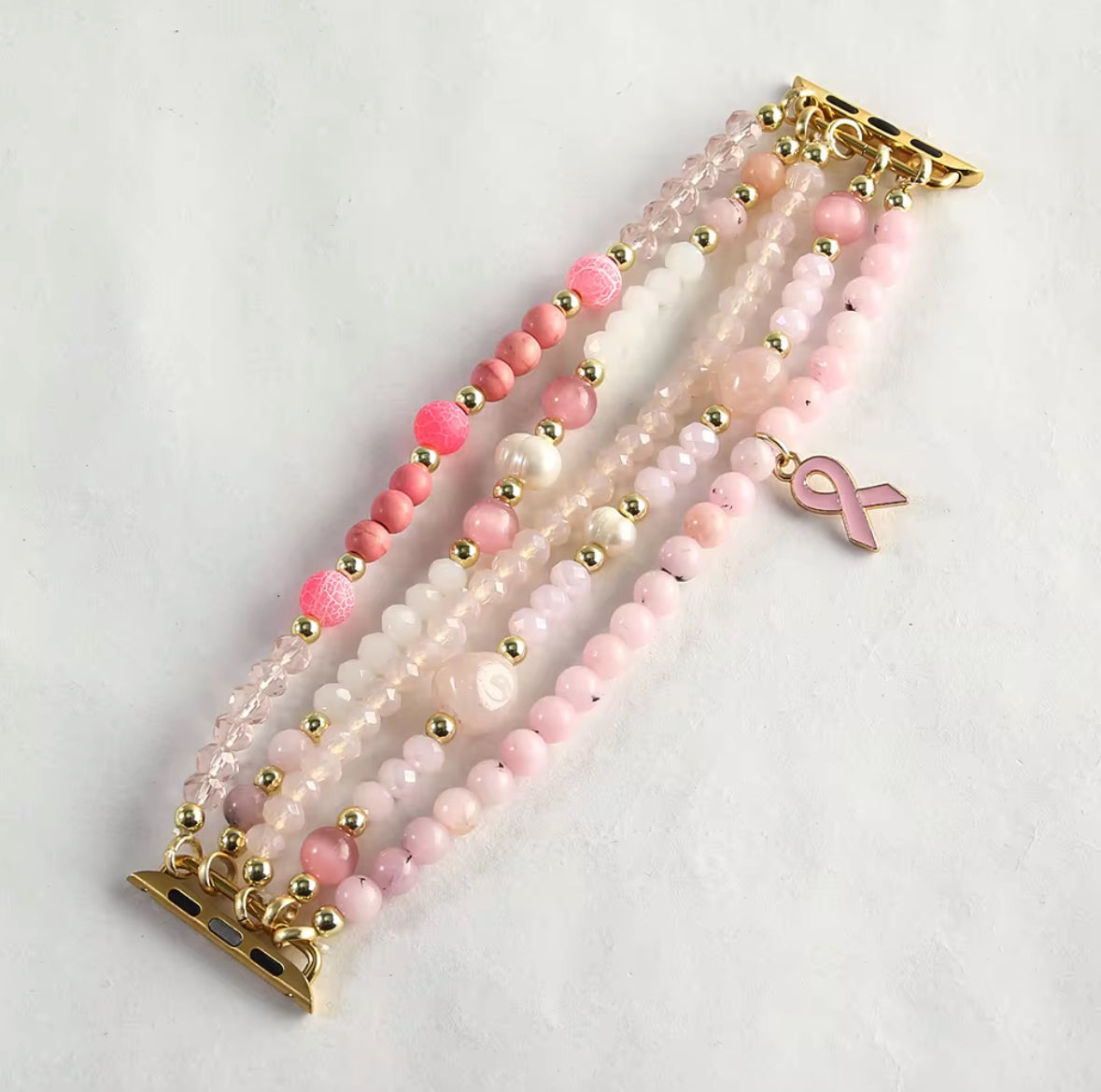 Beaded bracelet with pink ribbon charm on a light gray background