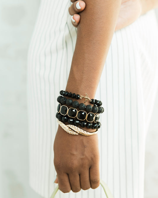 Black and gold beaded bracelet stack on wrist 