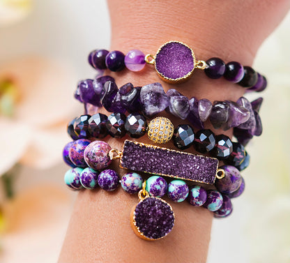 Stack of purple beaded bracelets on a wrist with a blurred background