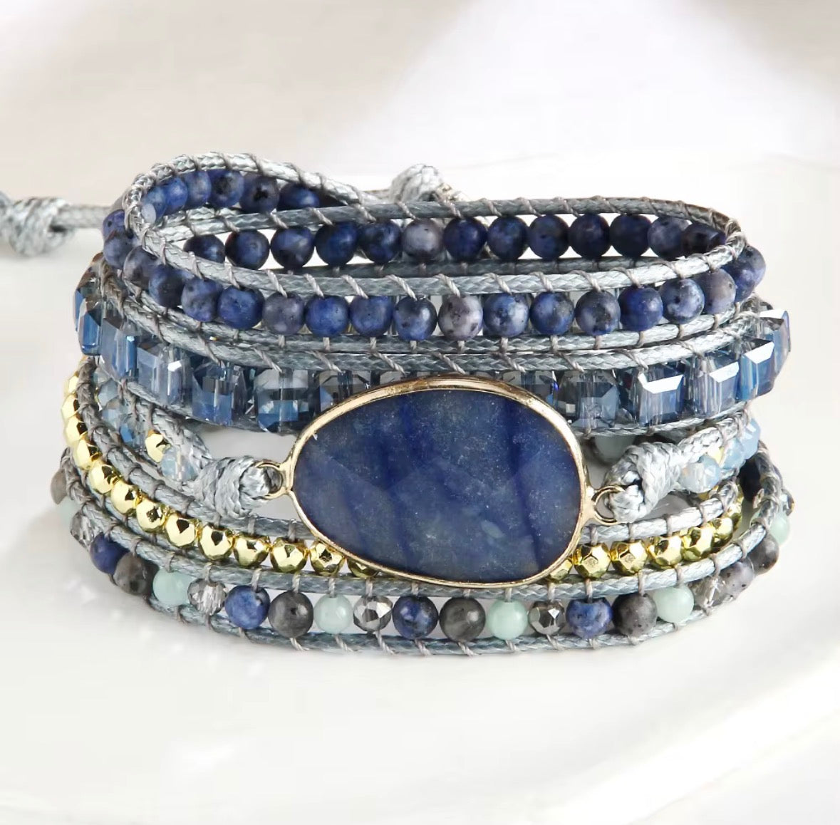 Multistrand bracelet with blue stones and gold accents on a white background