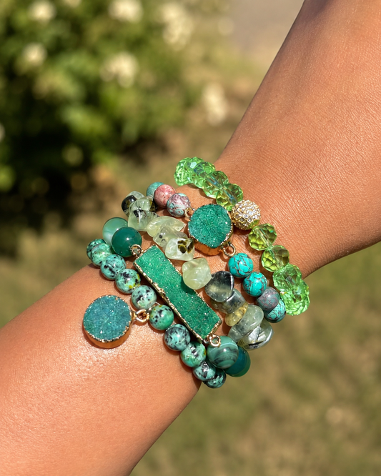 Multicolored beaded bracelets on a wrist with a blurred green outdoor background