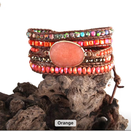 Multicolored beaded bracelet with a central orange stone on a textured surface
