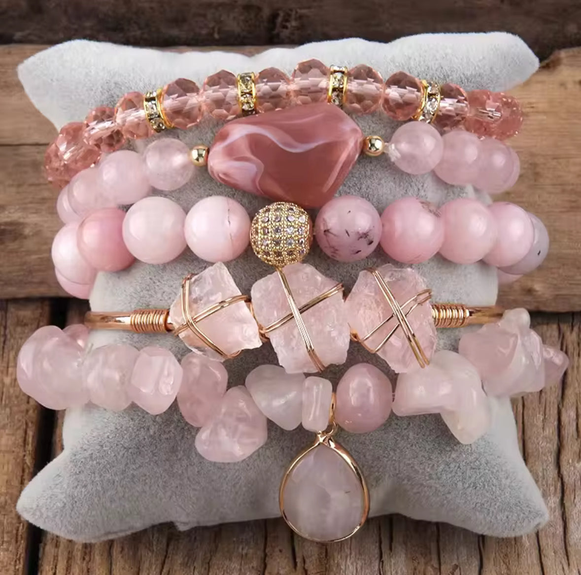 Stack of pink beaded bracelets with gold accents on a textured surface