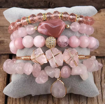 Stack of pink beaded bracelets with gold accents on a textured surface