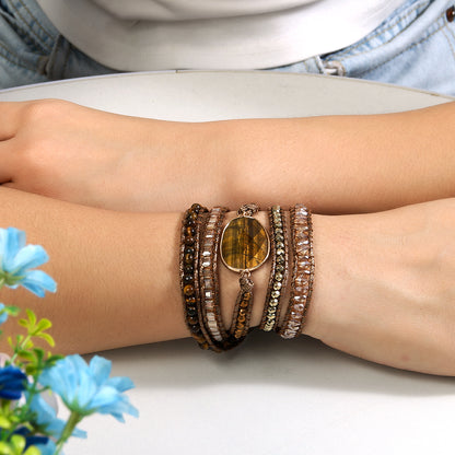 Close-up of a wrist wearing multiple bracelets with a floral background