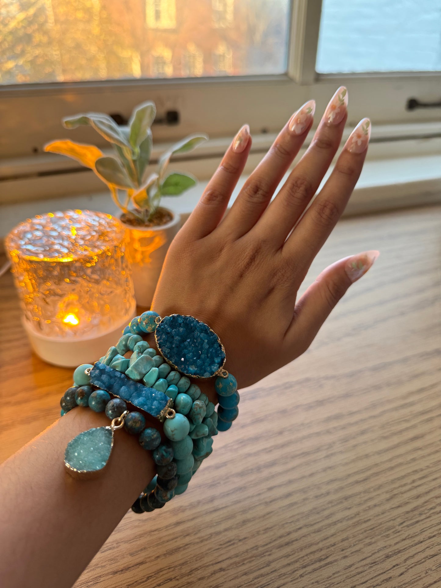 Hand wearing multiple turquoise bracelets with a warm light in the background