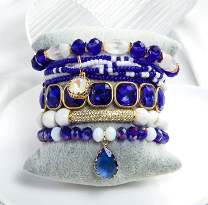 Stack of blue and white beaded bracelets on a textured white surface