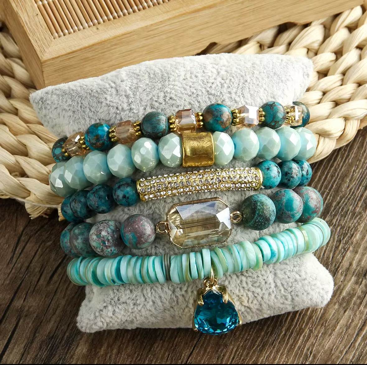 Stack of turquoise beaded bracelets with gold accents on a woven surface