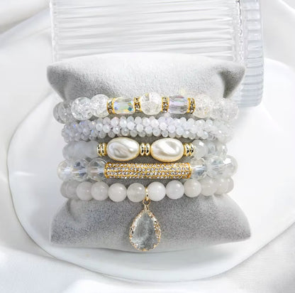 Stack of beaded bracelets with pearls and crystals on a white surface