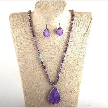Purple beaded necklace and earrings on a beige mannequin bust.